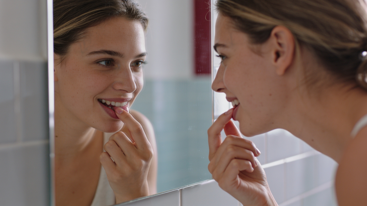 Woman checking her repaired tooth enamel in a mirror