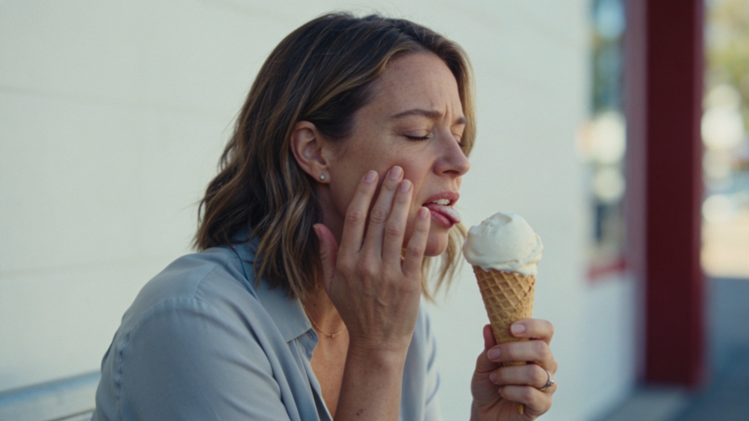 Woman wincing at cold ice cream with sensitive teeth